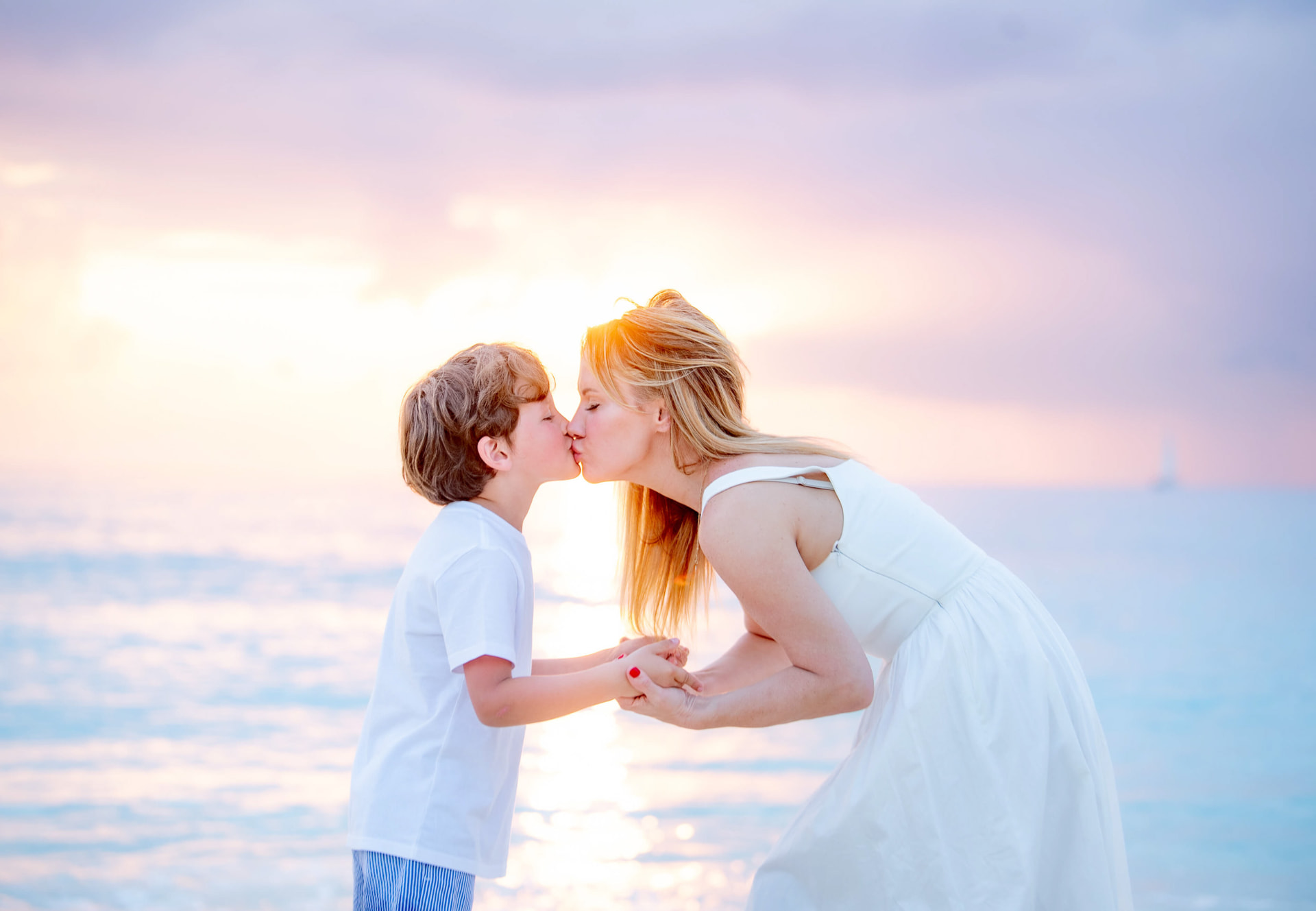 Mother and son sharing a tender sunset kiss on the beach